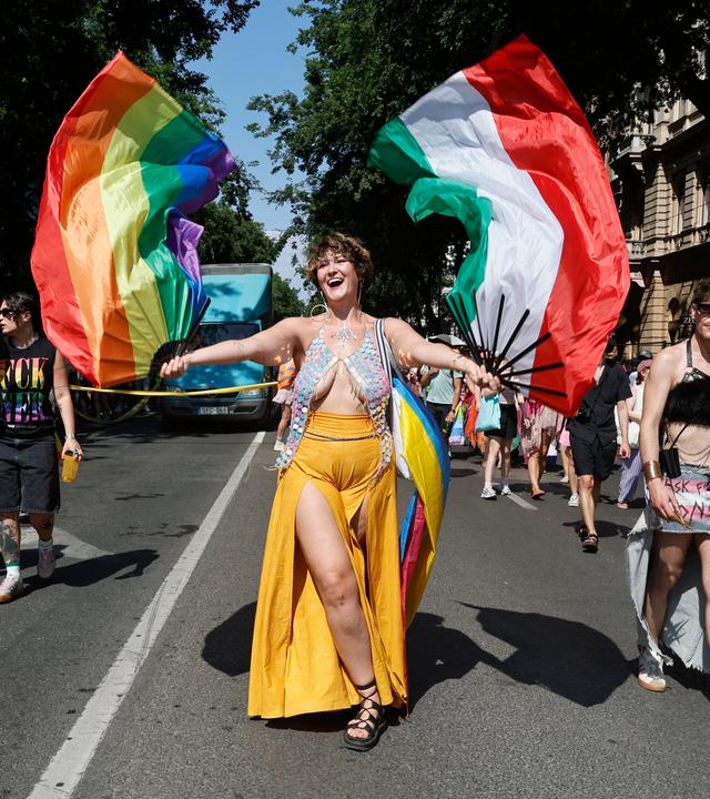 Teilnehmer marschieren während der 31. Budapest-Pride-Veranstaltung in der Innenstadt von Budapest, Ungarn. Eine Frau schwingt eine ungarische und eine Pride-Flagge.