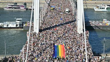Eine Menschenmenge trägt eine Regenbogenflagge, während sie am 28. Juni 2025 an der Pride-Parade im Stadtzentrum von Budapest teilnehmen.