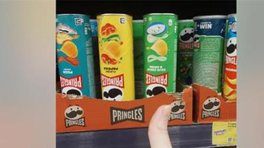 Eine Hand, die vor mehreren Pringles-Dosen den Daumen nach oben zeigt