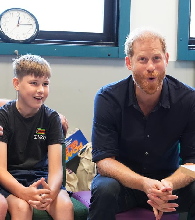 Prinz Harry (rechts) sitzt neben einem Kind