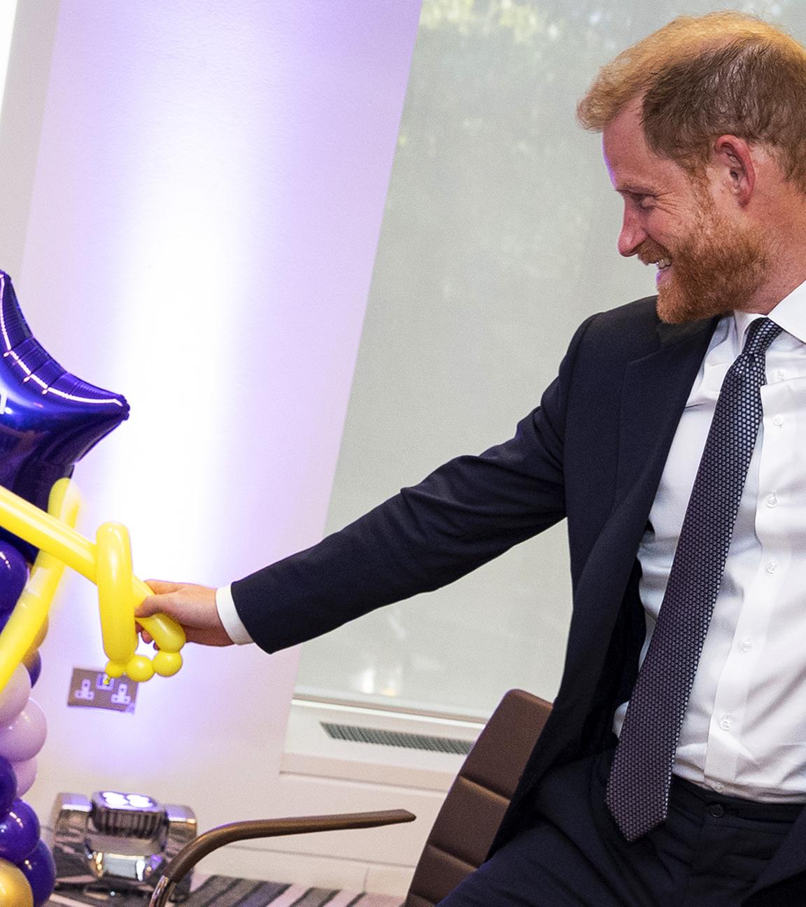 Prinz Harry, wie er bei den WellChild Awards mit einem Kind spielt. Sie spielen mit Luftballons.
