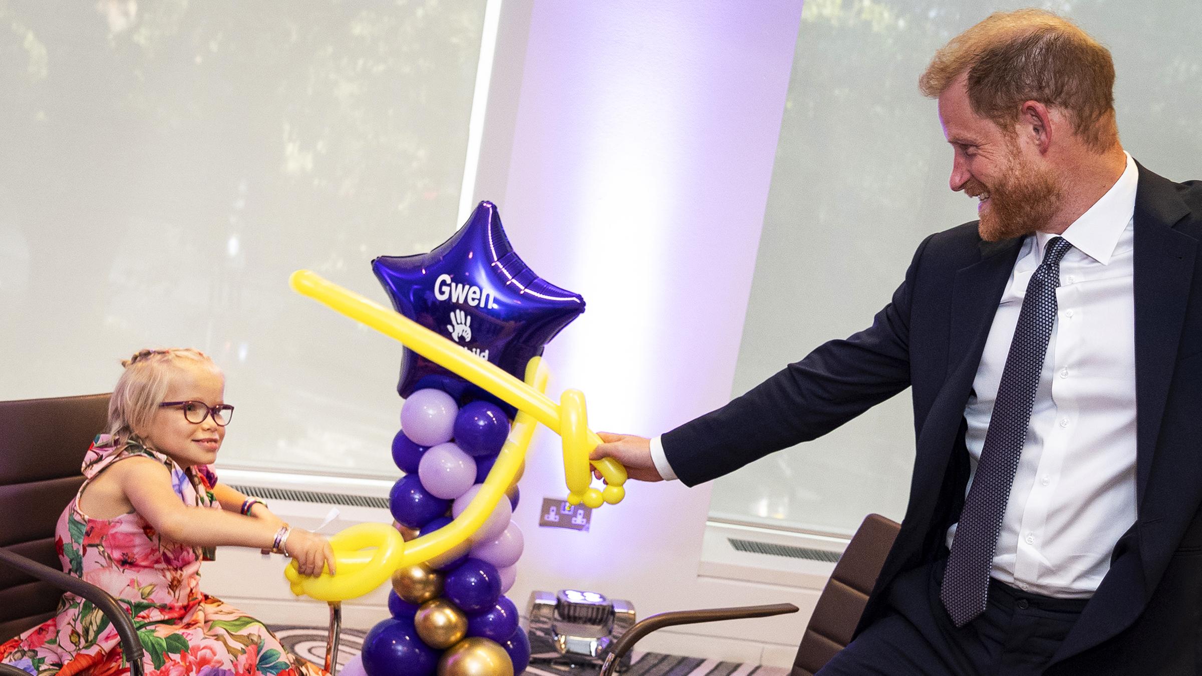 Prinz Harry, wie er bei den WellChild Awards mit einem Kind spielt. Sie spielen mit Luftballons.