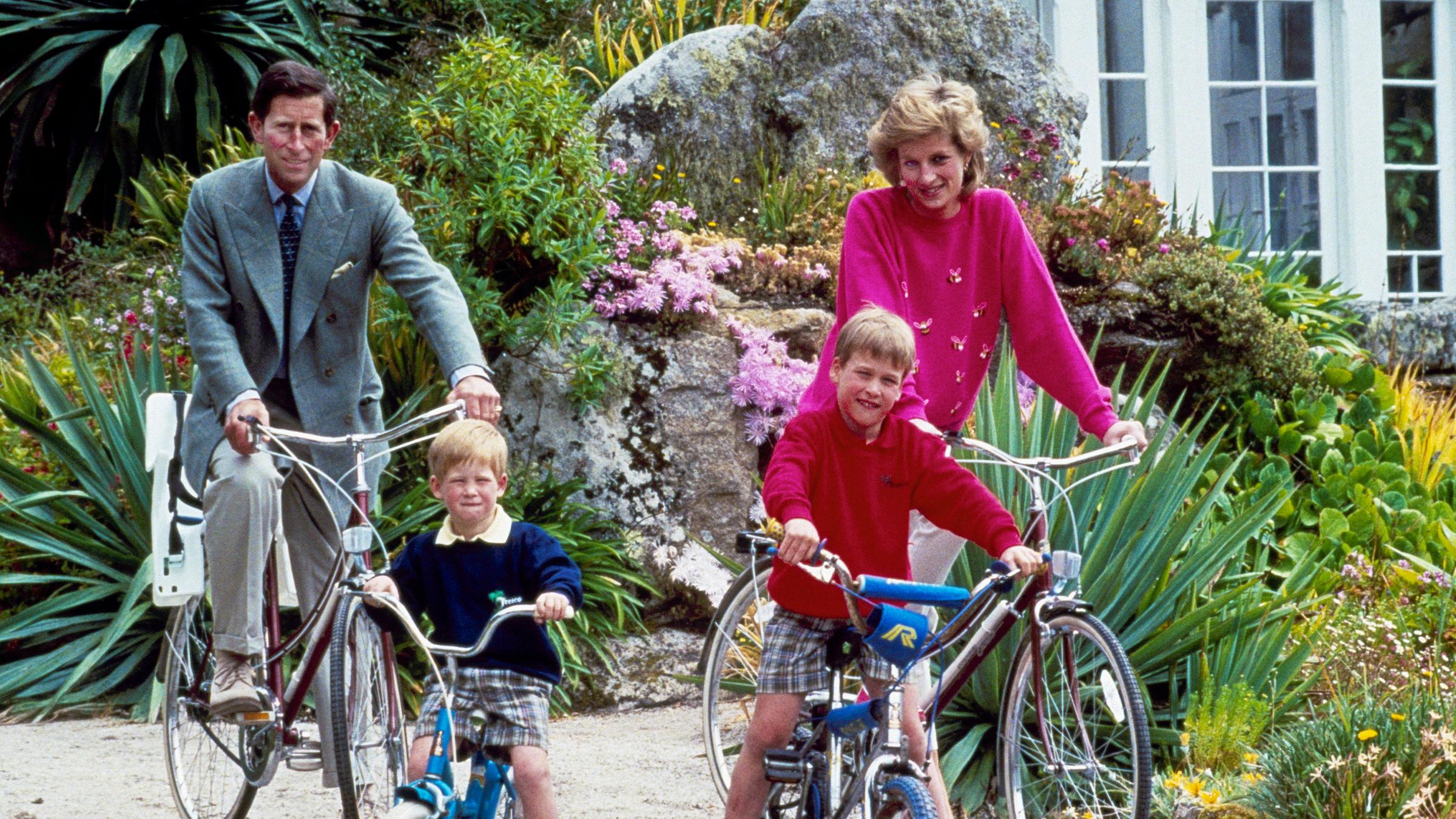Prinz Harry und William, Charles und Diana sitzen alle auf Fahrrädern und schauen in die Kamera.
