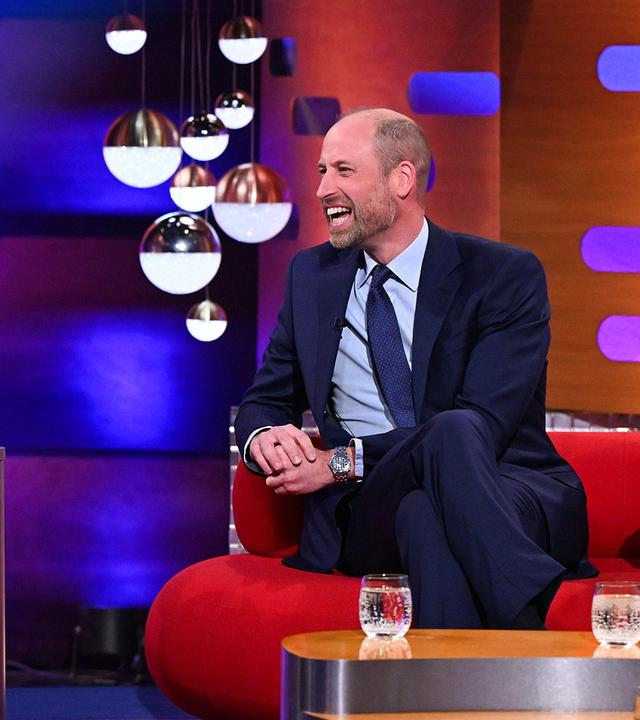 Prinz William sitzt auf einem roten Sofa und lächelt zum Moderator. 