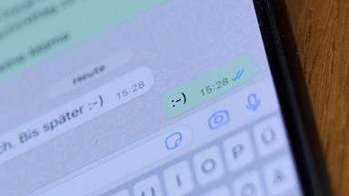 Illustration - Ein Smiley ist in einem Chat auf einem Handydisplay zu sehen.