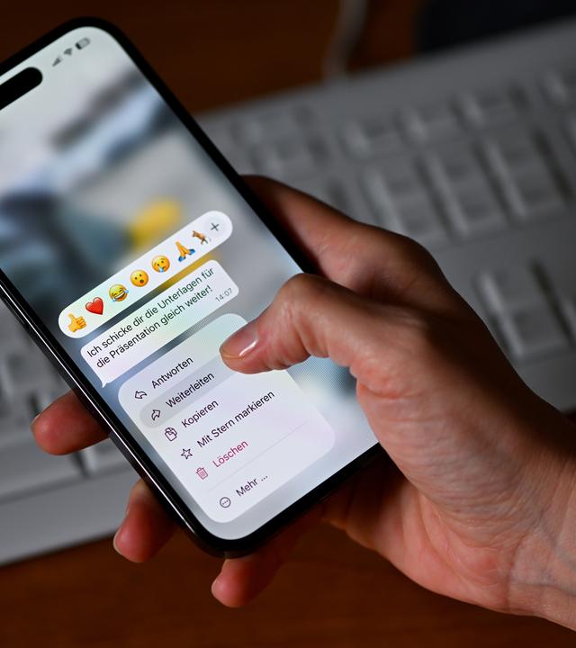 Symbolbild: Eine Frau hält ein Smartphone in der Hand und leitet eine Nachricht über einen Messenger-Dienst weiter. (gestellte Szene) 