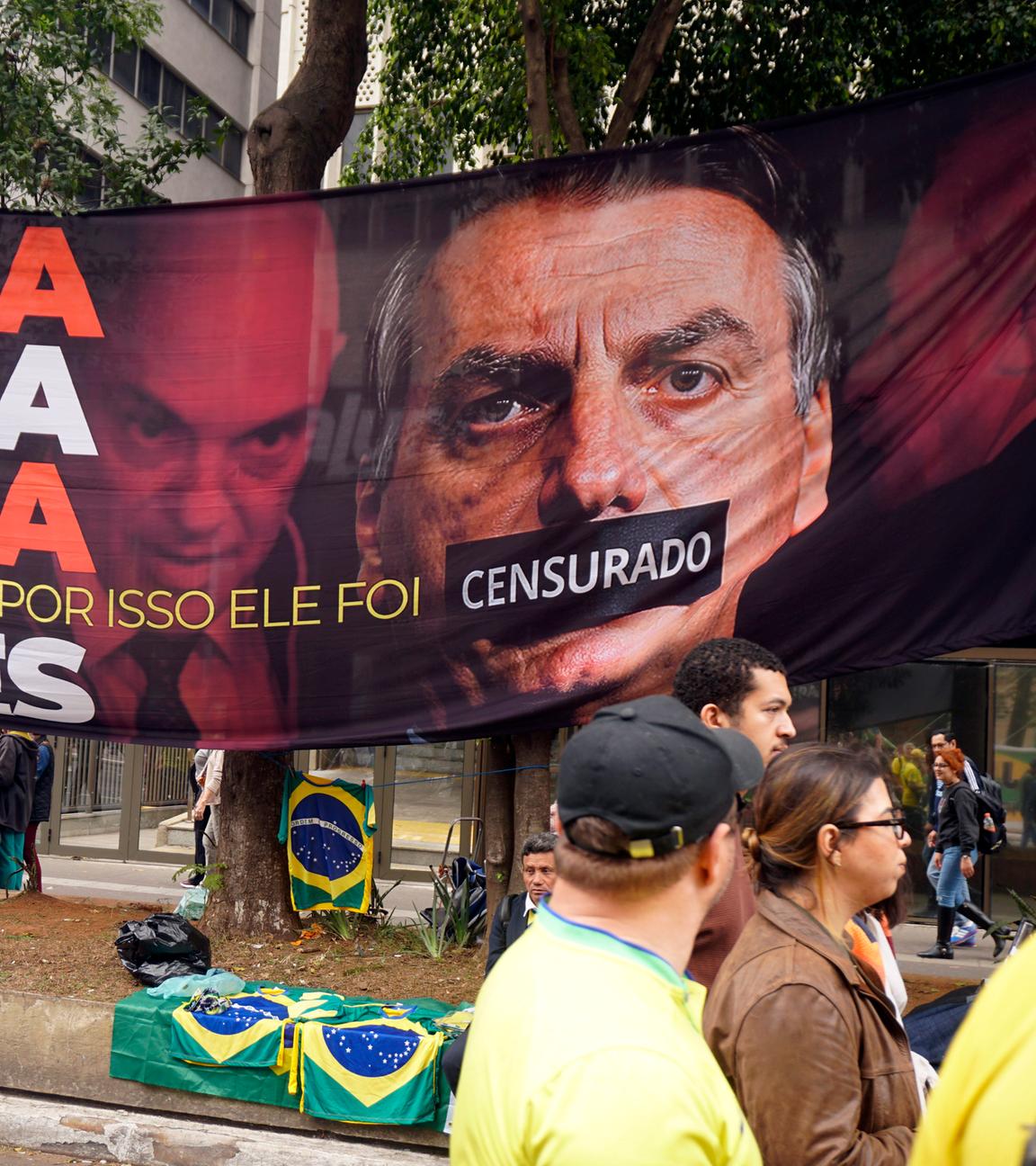 Eine Demonstration in Sao Paulo. Es wurde ein großes Plakat aufgehangen auf dem der ehemalige Präsident Bolsonaro abgebildet ist. Sein Mund wurde zugeklebt.