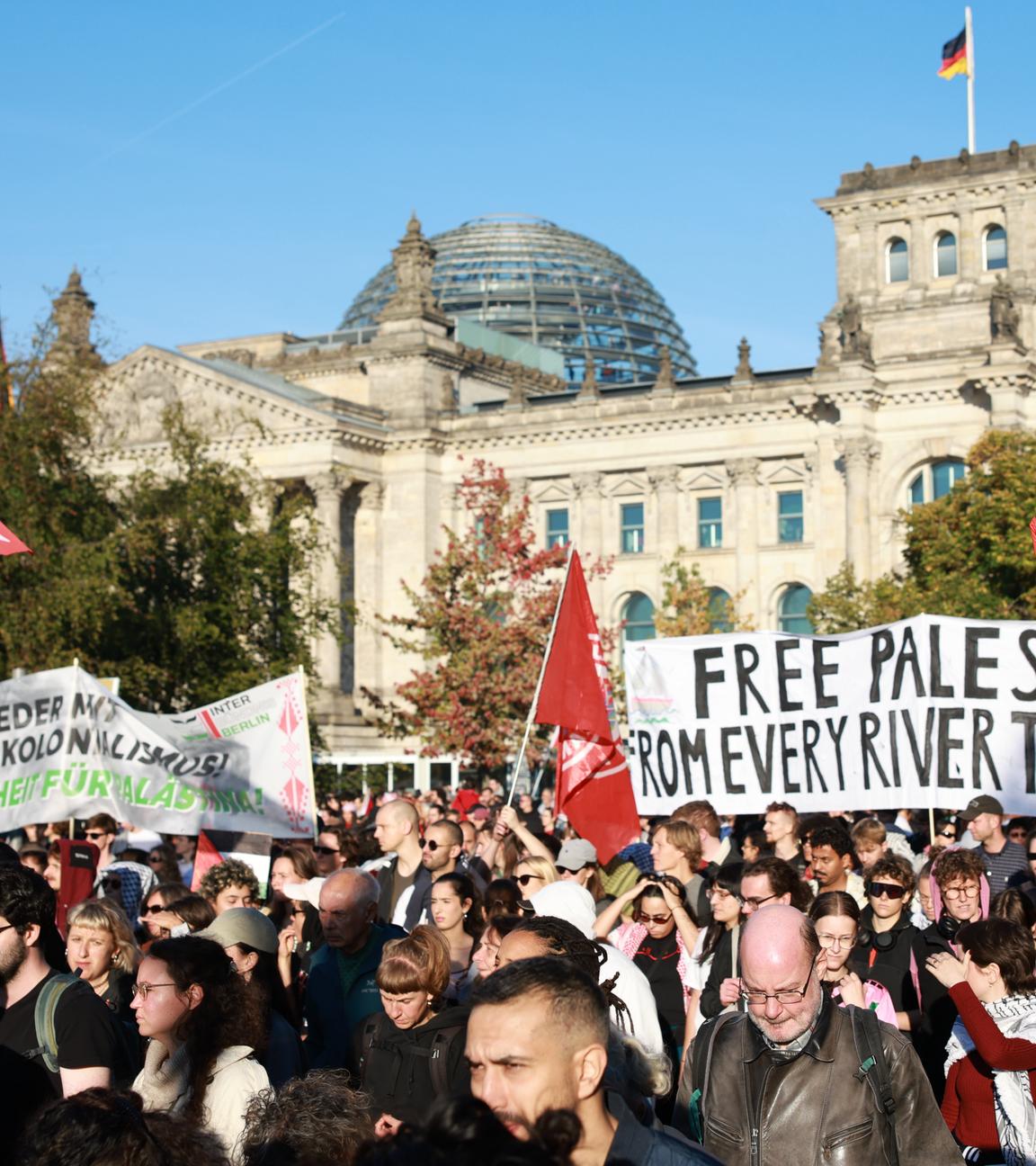 Eine Pro-Palästina Demo in Berlin vor dem Reichstagsgebäude. Die Demonstranten halten Plakate und Fahnen in die Luft
