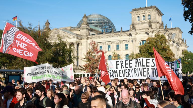 Eine Pro-Palästina Demo in Berlin vor dem Reichstagsgebäude. Die Demonstranten halten Plakate und Fahnen in die Luft