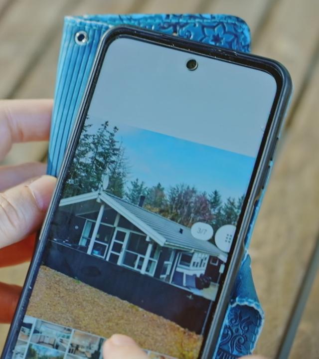 Person schaut sich auf dem Smartphone Ferienwohnungsbilder an
