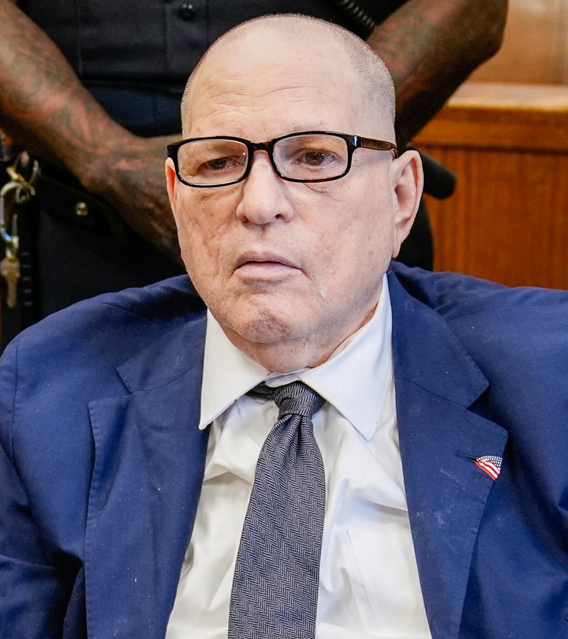 Star-Produzenten Harvey Weinstein sitzt in einem Gerichtssaal. Er trägt einen blauen Anzug und eine blaue Krawatte.