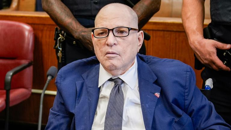 Star-Produzenten Harvey Weinstein sitzt in einem Gerichtssaal. Er trägt einen blauen Anzug und eine blaue Krawatte.