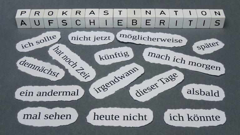 Schlagworte zum Thema Prokrastination liegen auf einem Untergrund.