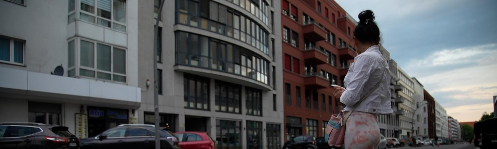 Eine Frau steht knapp bekleidet am Straßenrand.