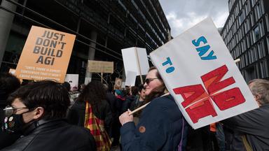 Demonstranten halten Schilder gegen KI hoch.