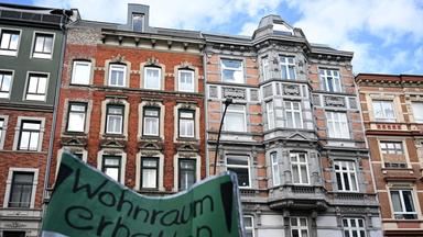 Ein Demonstrant hält ein Schild mit der Aufschrift "Wohnraum erhalten" bei einer Demonstration vor einem akut einsturzgefährdeten Mehrfamilienhaus in der Holstenstraße im Stadtteil Altona hoch.