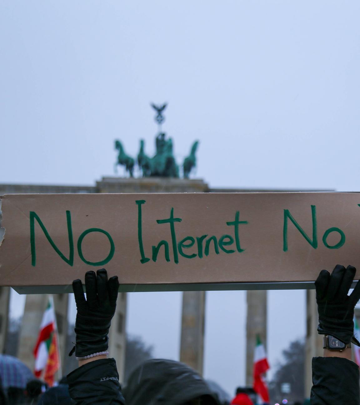 Exil-Iraner protestieren vor dem Brandenburger Tor gegen das islamische Regime im Iran. Im Vordergrund ist ein Schild mit der Aufschrift "No Internet, No Truth" zu sehen.