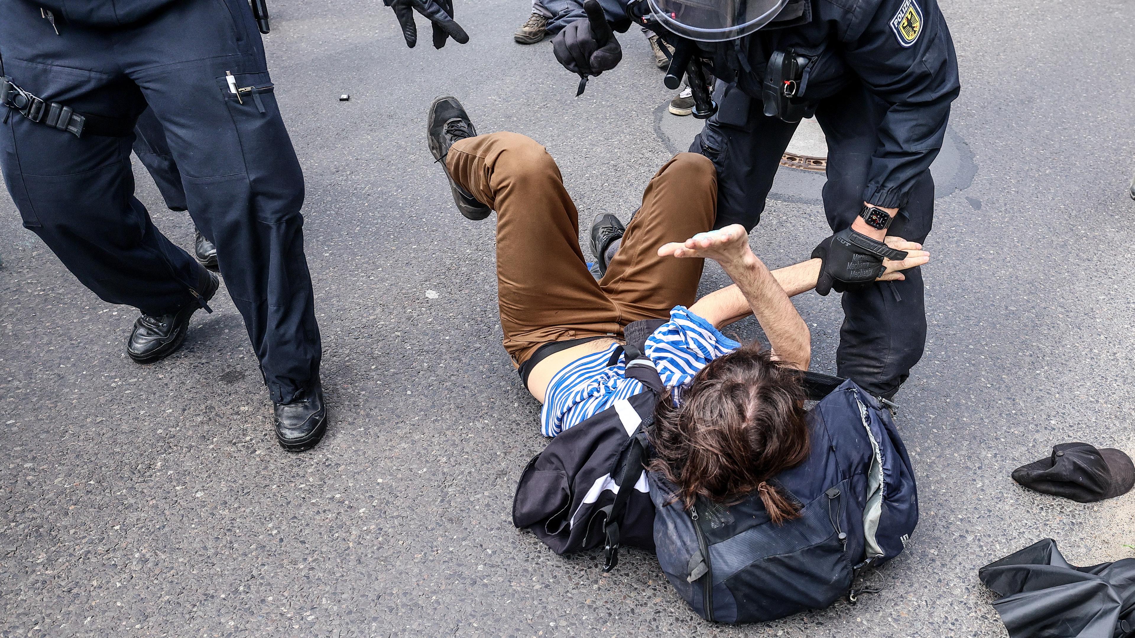 Polizisten diskutieren mit einem am Boden liegenden Demonstranten.