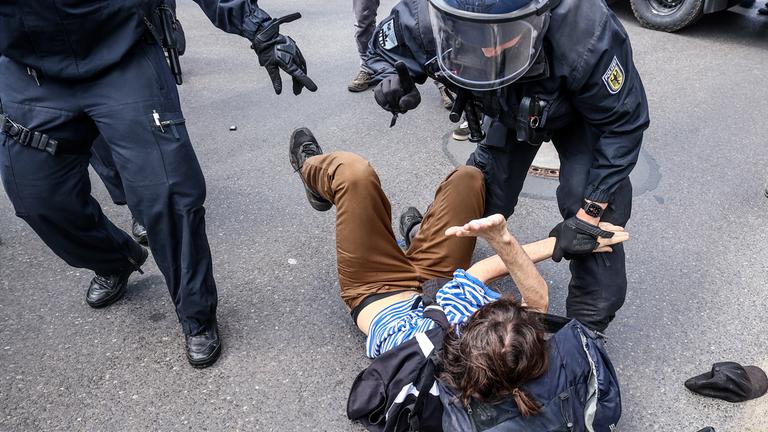 Polizisten diskutieren mit einem am Boden liegenden Demonstranten.