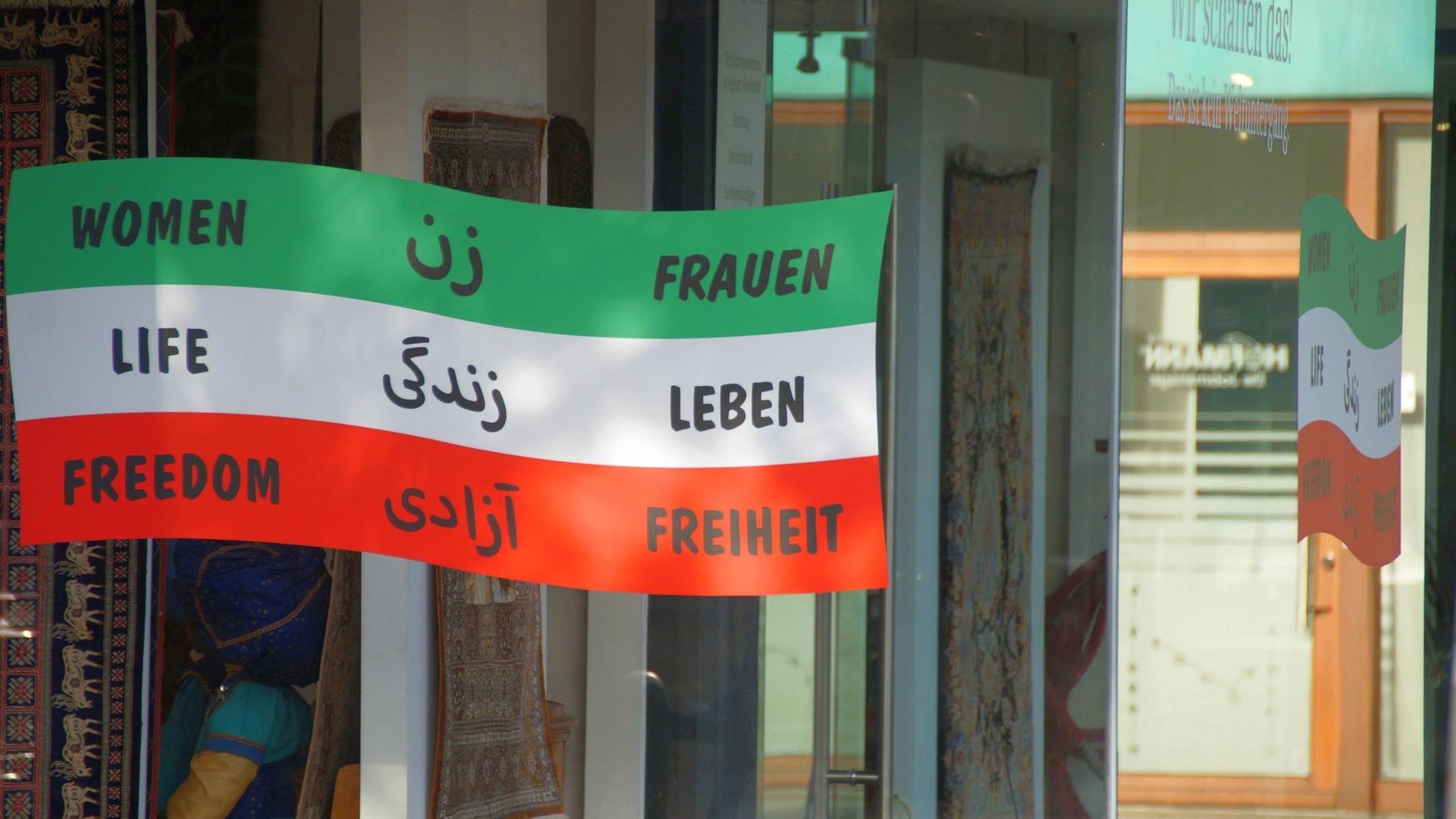 Aus Solidarität mit der Protestbewegung im Iran gegen das dortige Mullah-Regime hat ein Exil-Iraner in Bremen die Schaufenster seines Teppichgeschäfts mit Protestaufklebern versehen. 
