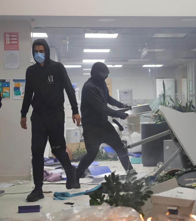 14.10.2026, Albanien, Tirana: Vermummte Demonstranten verwüsten während Zusammenstößen in Tirana, Albanien, eine Bank, als sich Studenten der regierungskritischen Flamingo-Bewegung anschlossen.