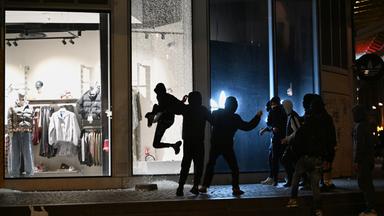Jugendliche zerschlagen im Zuge der Proteste in Paris am Abend eine Schaufensterscheibe.