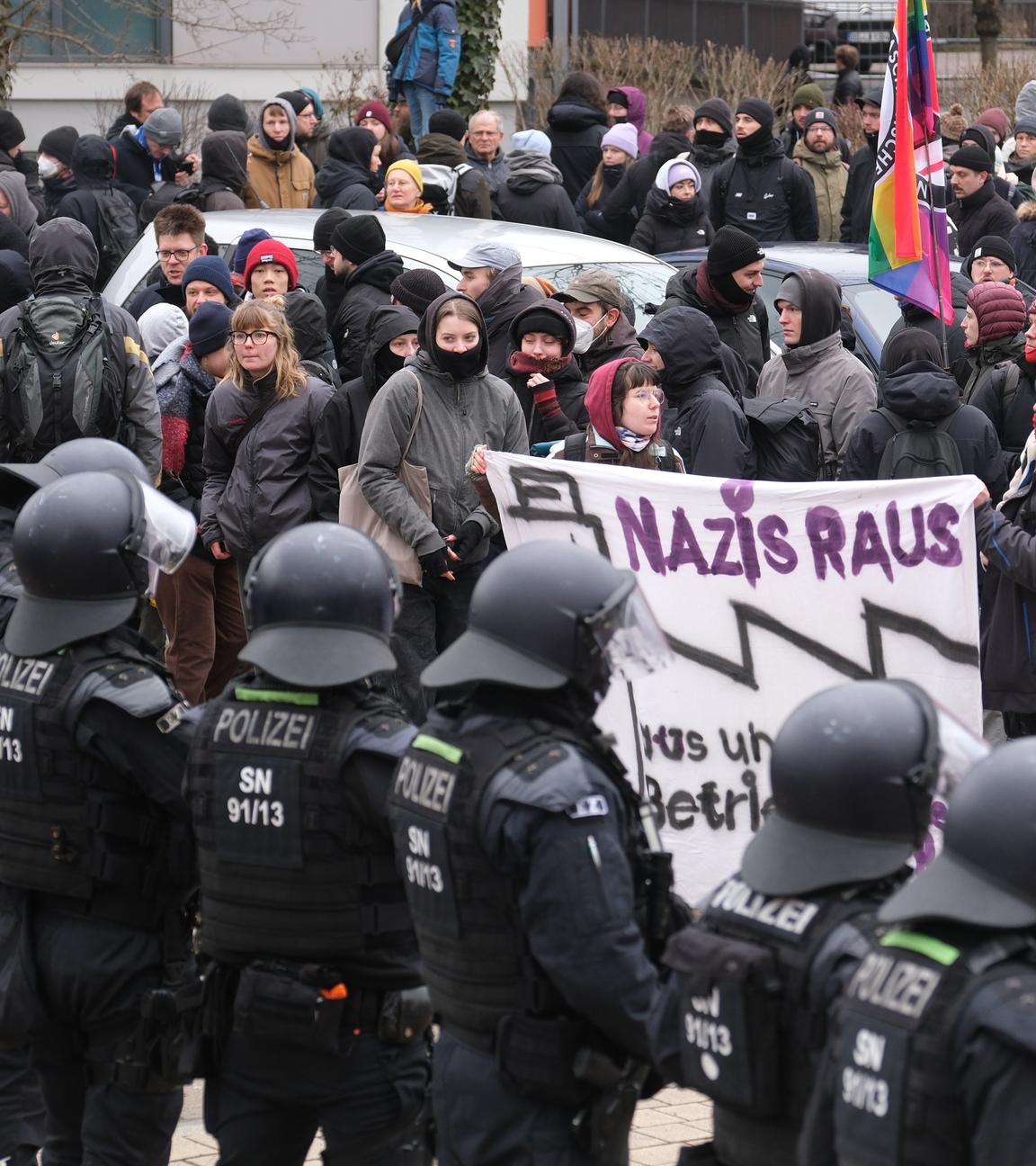 Sachsen, Dresden: Teilnehmer einer linken Demonstration stehen vor einer Absperrung der Polizei, die mit Wasserwerfern präsent sind.