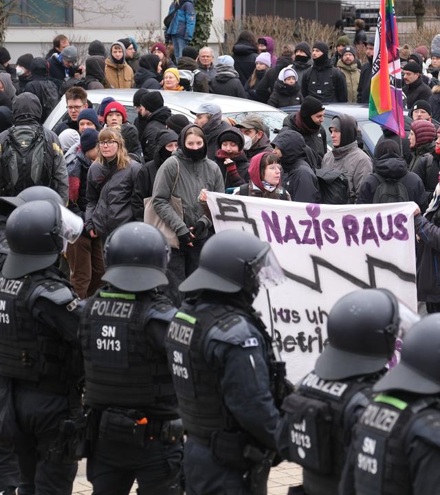 Sachsen, Dresden: Teilnehmer einer linken Demonstration stehen vor einer Absperrung der Polizei, die mit Wasserwerfern präsent sind.