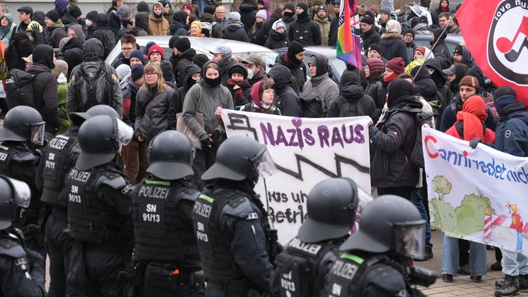 Sachsen, Dresden: Teilnehmer einer linken Demonstration stehen vor einer Absperrung der Polizei, die mit Wasserwerfern präsent sind.