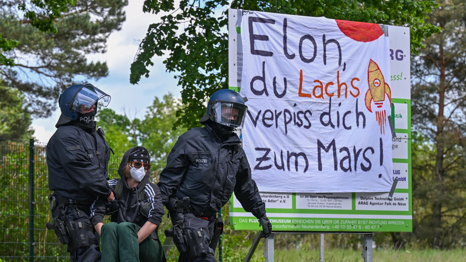 Polizisten tragen einen Aktivisten von der Zufahrt zum Flugplatz Neuhardenberg weg. 