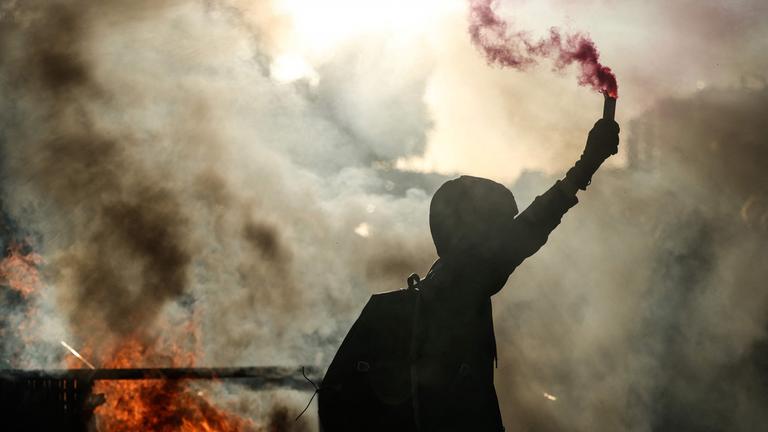 Ein Demonstrant schwenkt eine Rauchflamme neben einer brennenden Barrikade während einer Demonstration der Protestbewegung „Bloquons tout“ („Lasst uns alles blockieren“) im Südosten von Paris am 10. 9. 2025.
