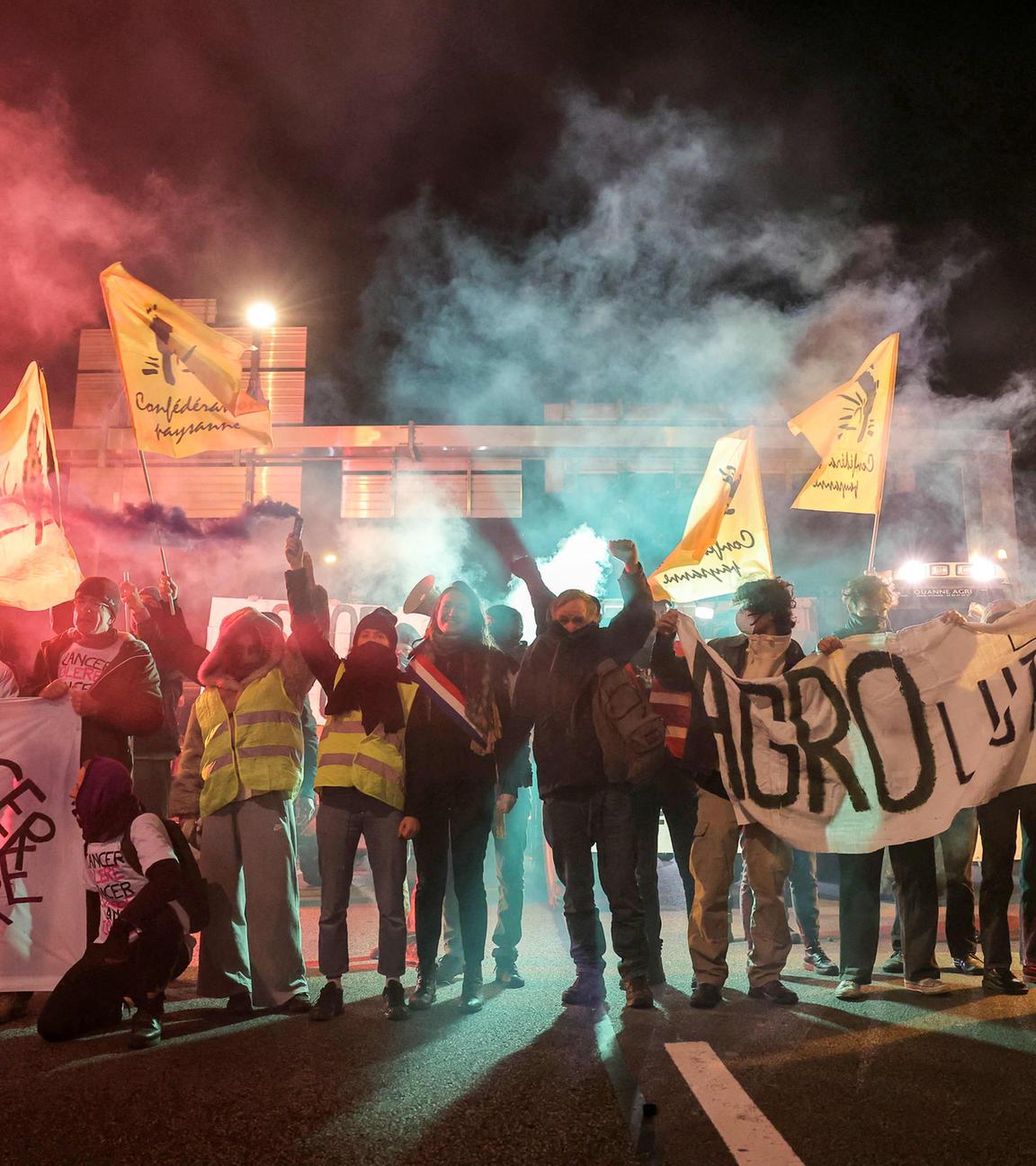Mitglieder des Bauernverbandes Confederation Paysanne halten Transparente hoch, um den Traktorenverkehr auf dem Pariser Autobahnring bei Porte de Montreuil zu verlangsamen. 