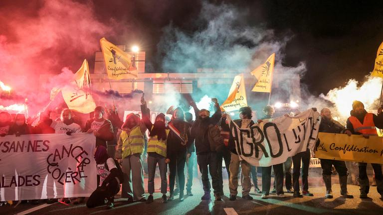 Mitglieder des Bauernverbandes Confederation Paysanne halten Transparente hoch, um den Traktorenverkehr auf dem Pariser Autobahnring bei Porte de Montreuil zu verlangsamen. 
