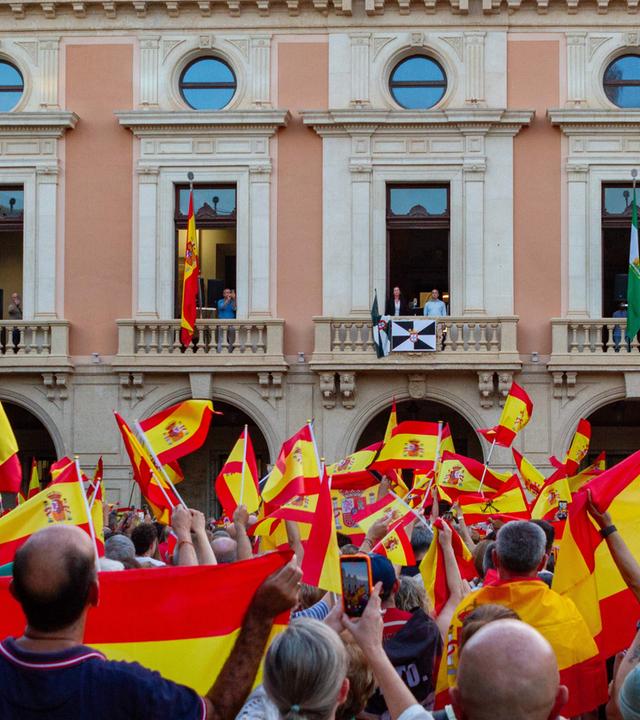 Menschen demonstrieren in Spanien mit ihrer Nationalflagge gegen die Migrationspolitik der Regierung.