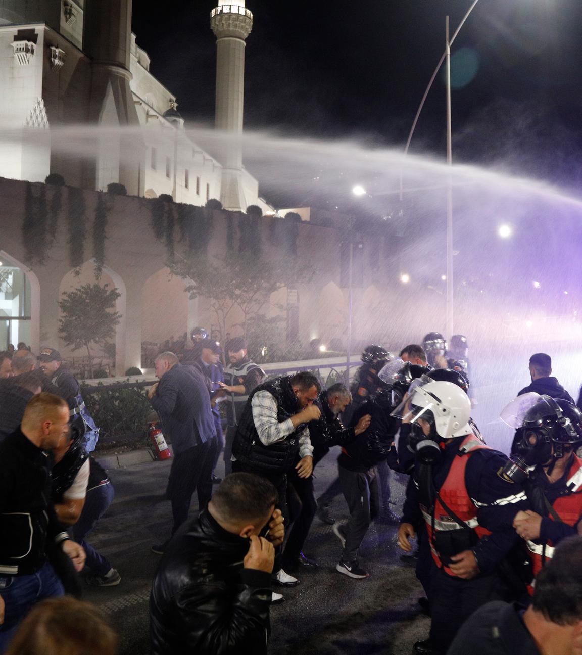 Demonstrierende auf den Straßen von Tirana. Die Polizei spritzt mit einem Wasserwerfer auf die Menschen.