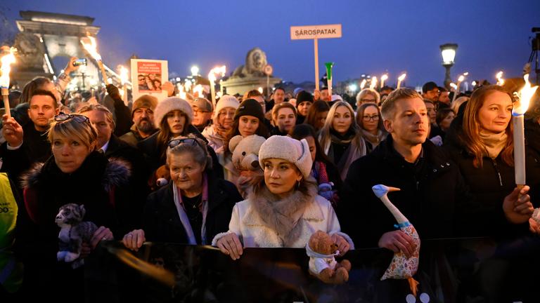 Menschen in Ungarn ziehen mit Schildern und einem Banner durch die Straßen in Budapest, um gegen die Orban-Regierung zu protestieren