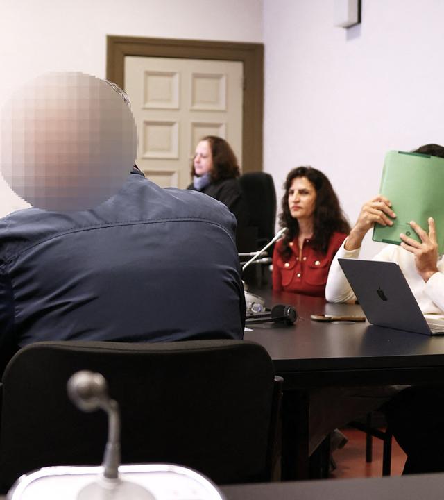 Der Hauptangeklagte (2.v.l), der Mitangeklagte (2.v.r), die Anwälte Shahryar Ebrahim-Nesbat (l) und Nawied Haschmizada (r), Verteidiger der Angeklagten, sowie eine Dolmetscherin und eine Gerichtsmitarbeiterin sitzen im Sitzungssaal.