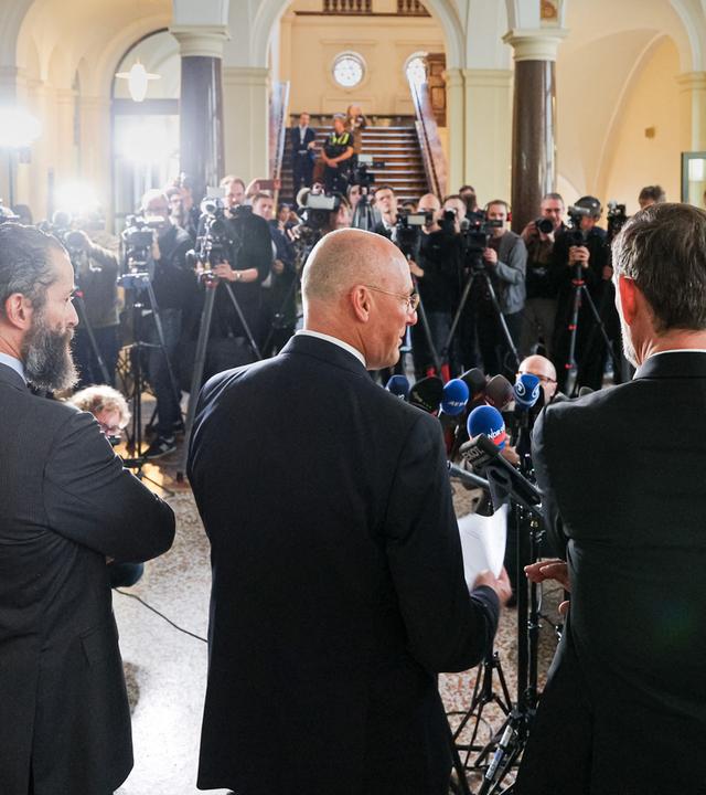  Die Verteidiger des Angeklagten, Nicola Canestrini (l-r), Jes Meyer Lohkamp und Lars Brögeler, sprechen nach Abschluss des ersten Prozesstags zu Pressevertretern.