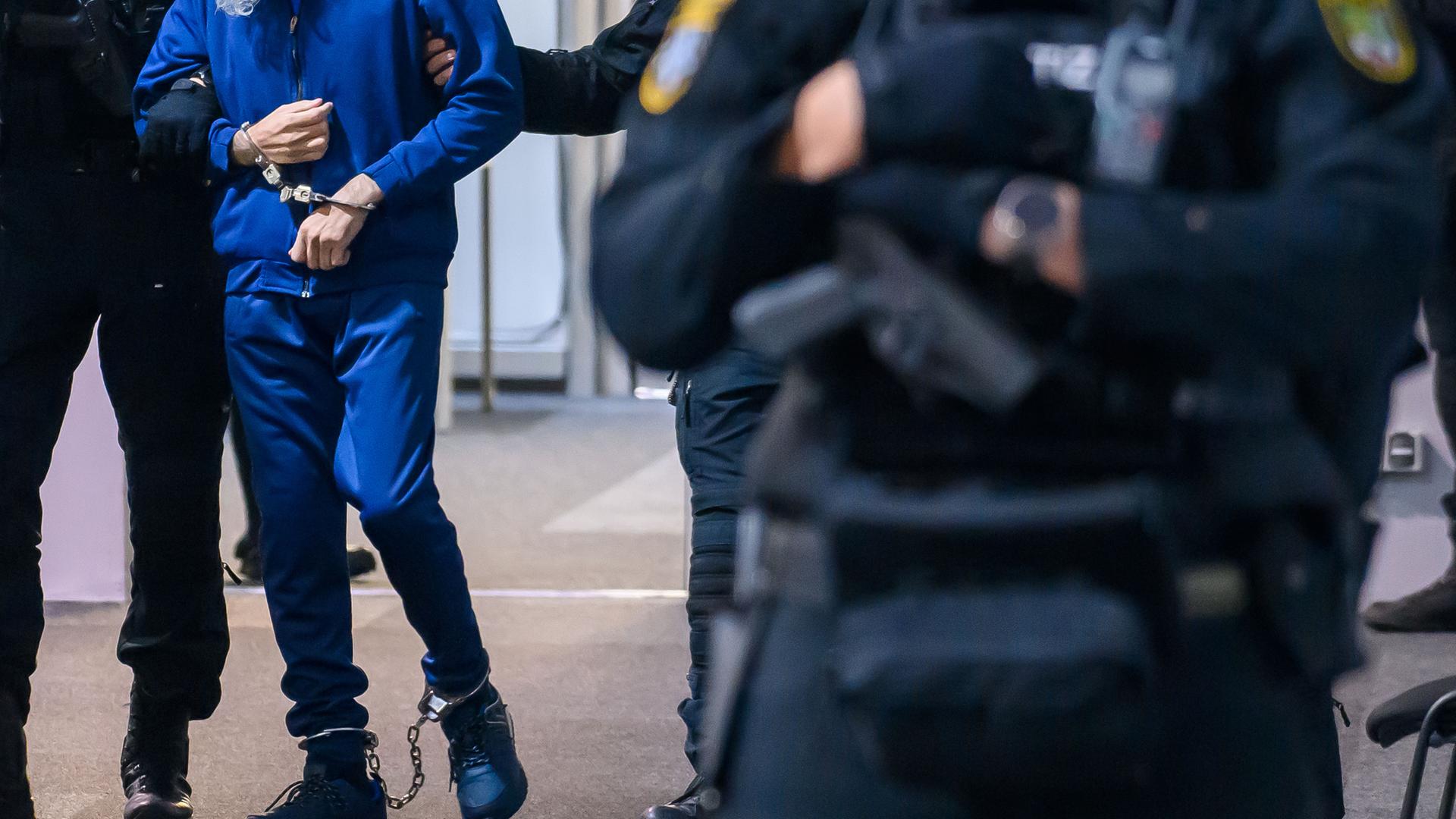 Justizbeamte führen den an Händen und Füßen gefesselten Angeklagten Taleb A. in den Gerichtssaal im Landgericht Magdeburg. 