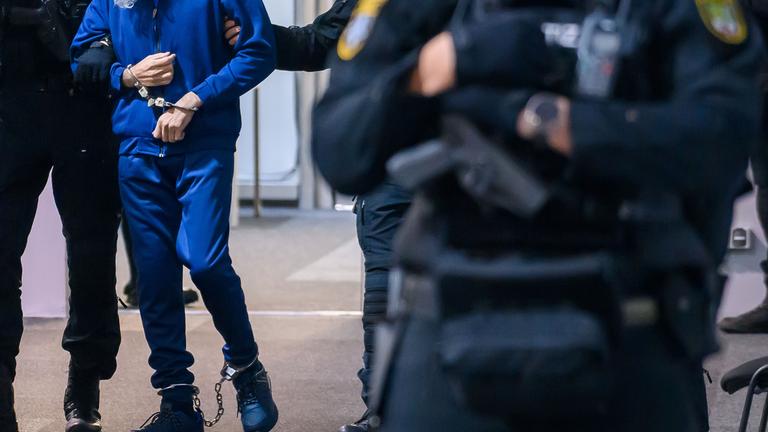 Justizbeamte führen den an Händen und Füßen gefesselten Angeklagten Taleb A. in den Gerichtssaal im Landgericht Magdeburg. 