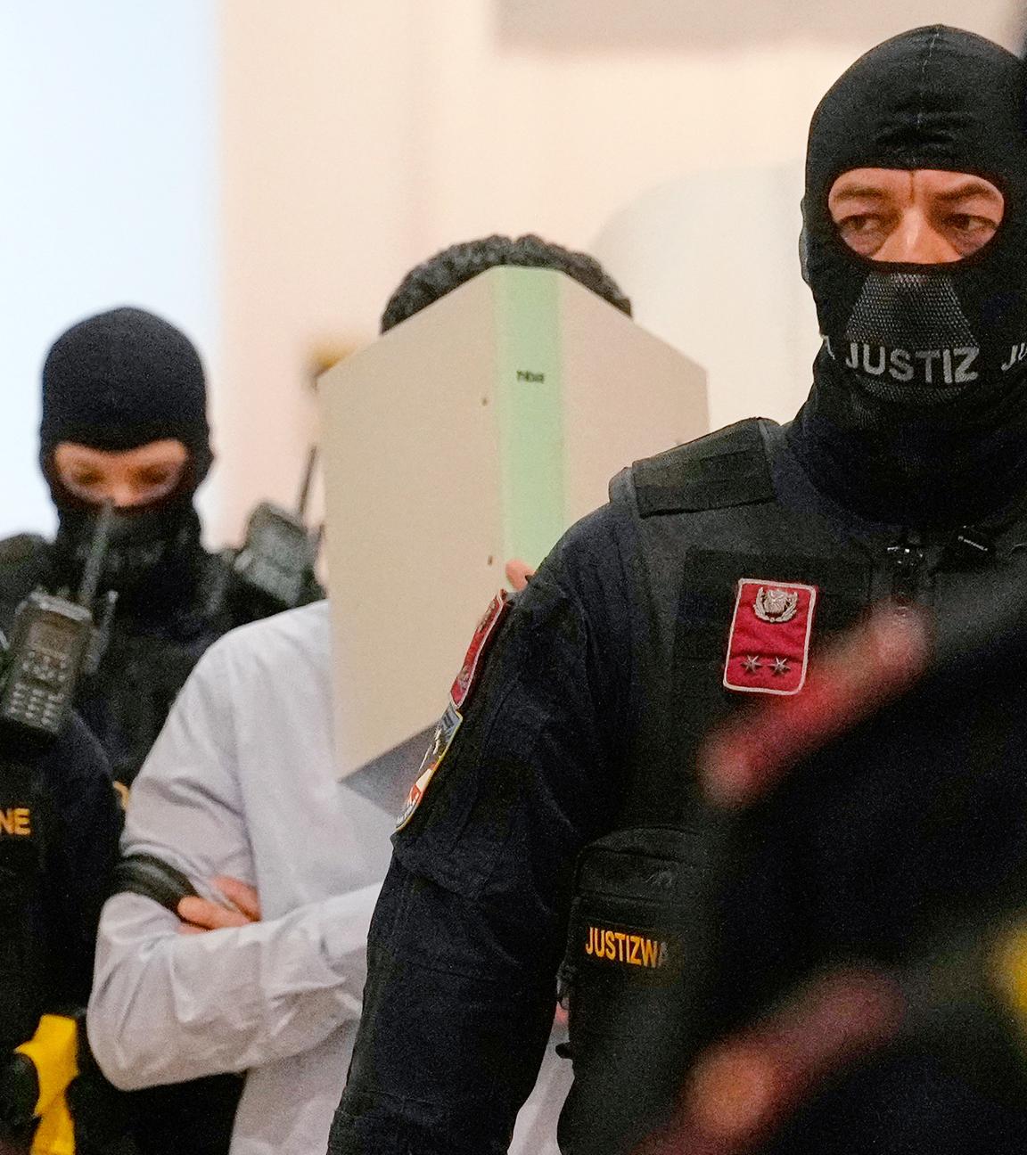 Ein Angeklagter verdeckt sein Gesicht mit einem Aktenordner, während er auf dem Weg in den Gerichtssaal des Bezirksgerichts ist, aufgenommen am 28.04.2026 in Wien (Österreich)