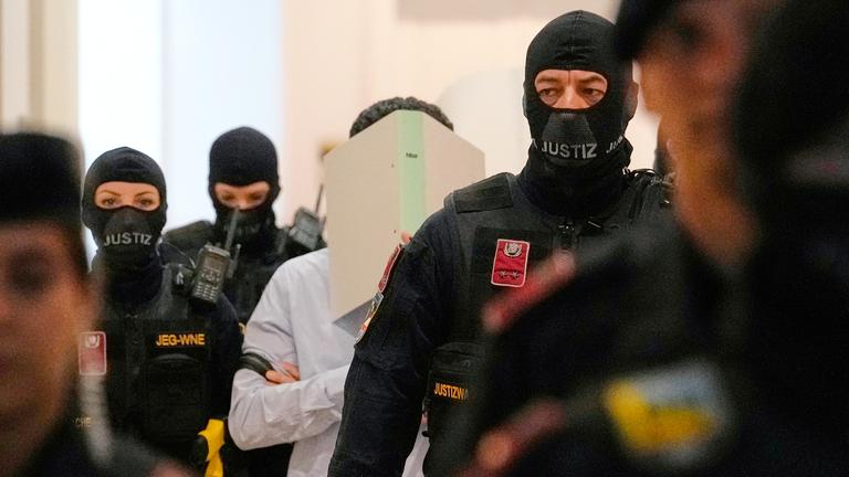 Ein Angeklagter verdeckt sein Gesicht mit einem Aktenordner, während er auf dem Weg in den Gerichtssaal des Bezirksgerichts ist, aufgenommen am 28.04.2026 in Wien (Österreich)