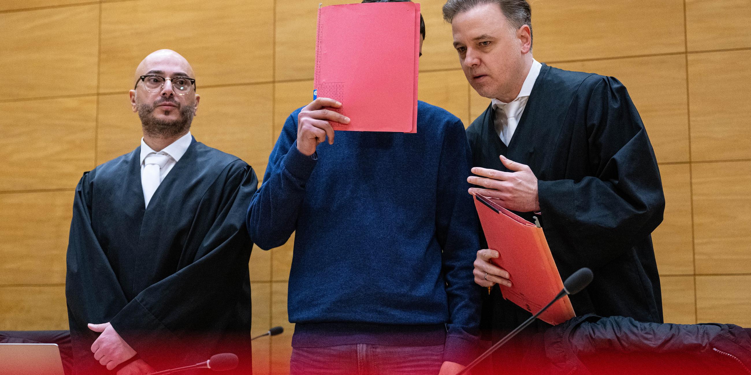 Einer der Angeklagten (M) steht mit seinen beiden Anwälten Burkhard Benecken (r) und Baris Devletli beim Beginn des Prozesses um den Totschlag nach einer Abifeier in Bad Oeynhausen vor dem Landgericht. aufgenommen am 17.12.2024 in Bielerfeld