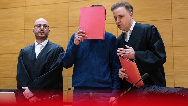 Einer der Angeklagten (M) steht mit seinen beiden Anwälten Burkhard Benecken (r) und Baris Devletli beim Beginn des Prozesses um den Totschlag nach einer Abifeier in Bad Oeynhausen vor dem Landgericht. aufgenommen am 17.12.2024 in Bielerfeld