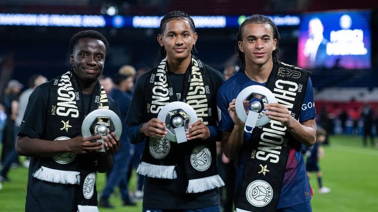 Die PSG-Spieler Yoram Zague, Senny Mayulu und Ethan Mbappe (von links) zeigen nach dem Gewinn der französischen Meisterschaft eine Trophäe am 12. Mai 2024