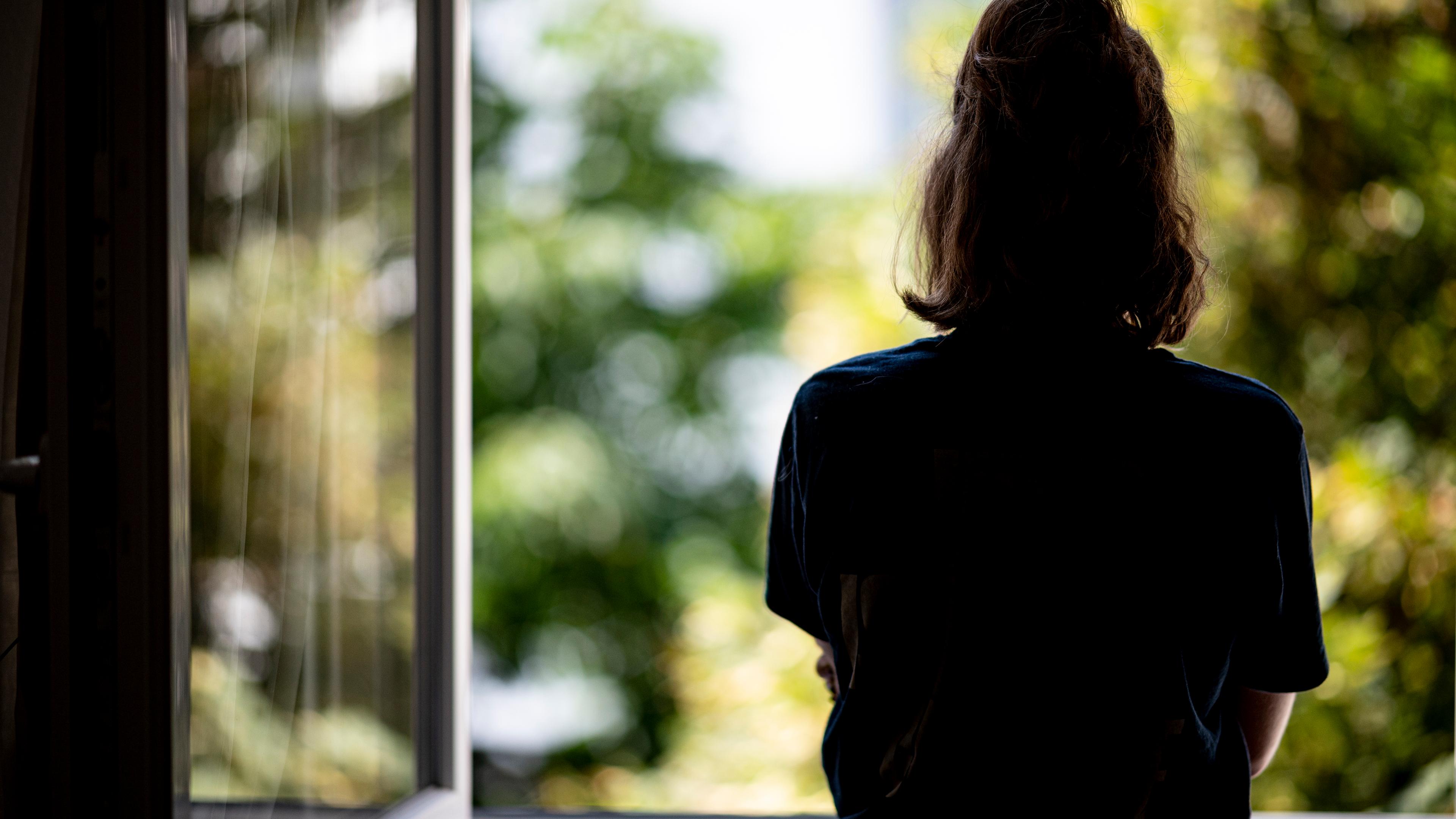 Berlin: Eine Frau steht in ihrer Wohnung an einem Fenster.