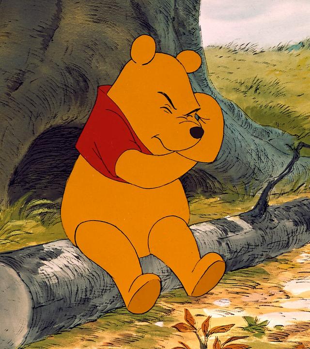 Szene aus dem Walt Disney-Zeichentrickfilm "Winnie The Pooh": Pu sitzt auf einem liegenden Baumstamm.