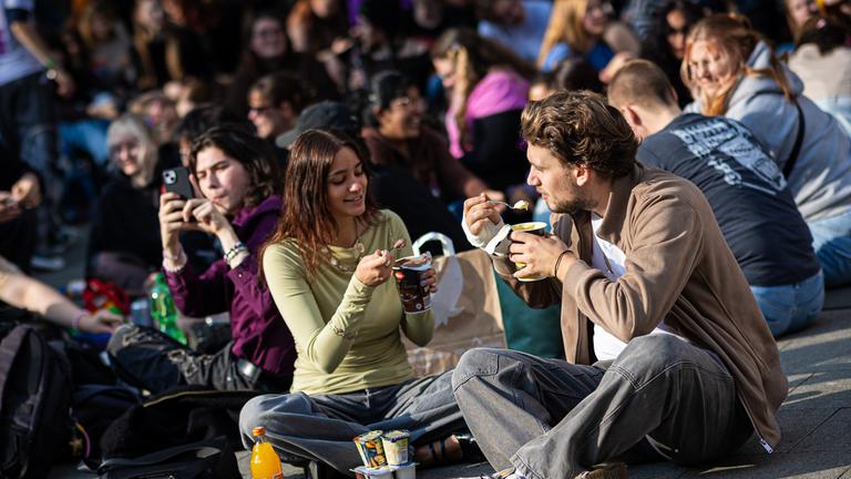 Zahlreiche Menschen treffen sich am Küchengarten, einem Platz in Hannover, um Pudding mit Gabeln zu essen.