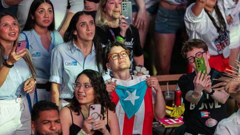 Fans in San Juan, Puerto Rico, verfolgen Bad Bunnys Auftritt im Fernsehen während der Halbzeitpause des Super Bowls. Ein Junge hält die Flagge Puerto-Ricos vor sich.