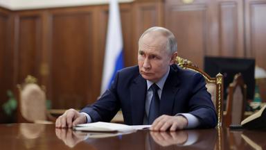 Wladimir Putin sitzt an einem großen Tisch und schaut in die Ferne.